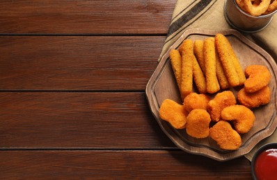 Tasty ketchup, chicken nuggets and cheese sticks on wooden table, flat lay. Space for text