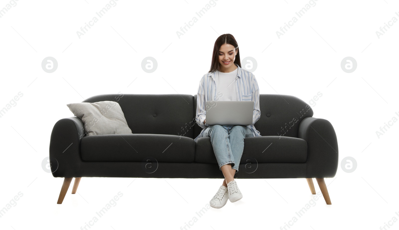 Photo of Young woman with laptop on comfortable grey sofa against white background