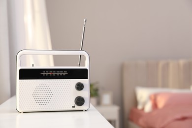 Stylish radio receiver on white table in bedroom, space for text