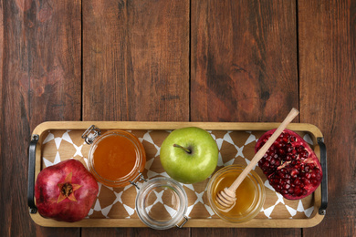 Photo of Honey, apples and pomegranate on wooden table, top view with space for text. Rosh Hashanah holiday