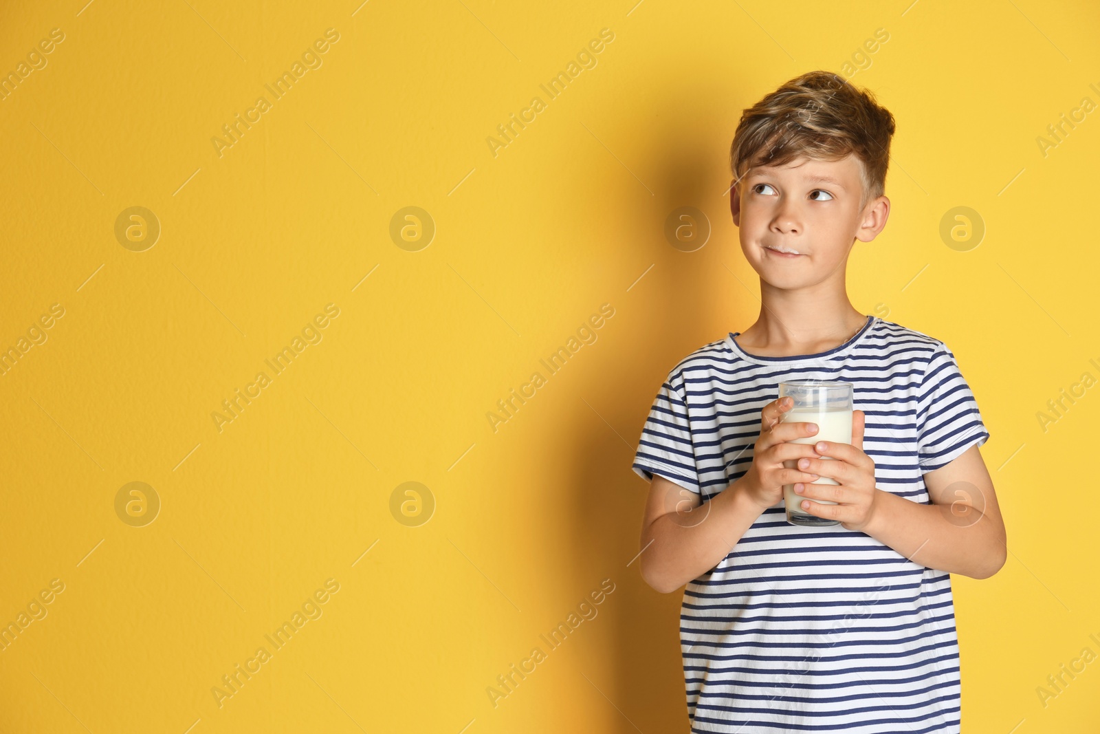 Photo of Adorable little boy with glass of milk on color background