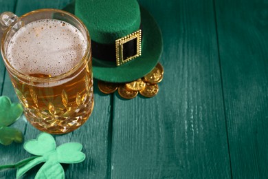 St. Patrick's day. Beer, leprechaun hat, gold and decorative clover leaves on green wooden table. Space for text