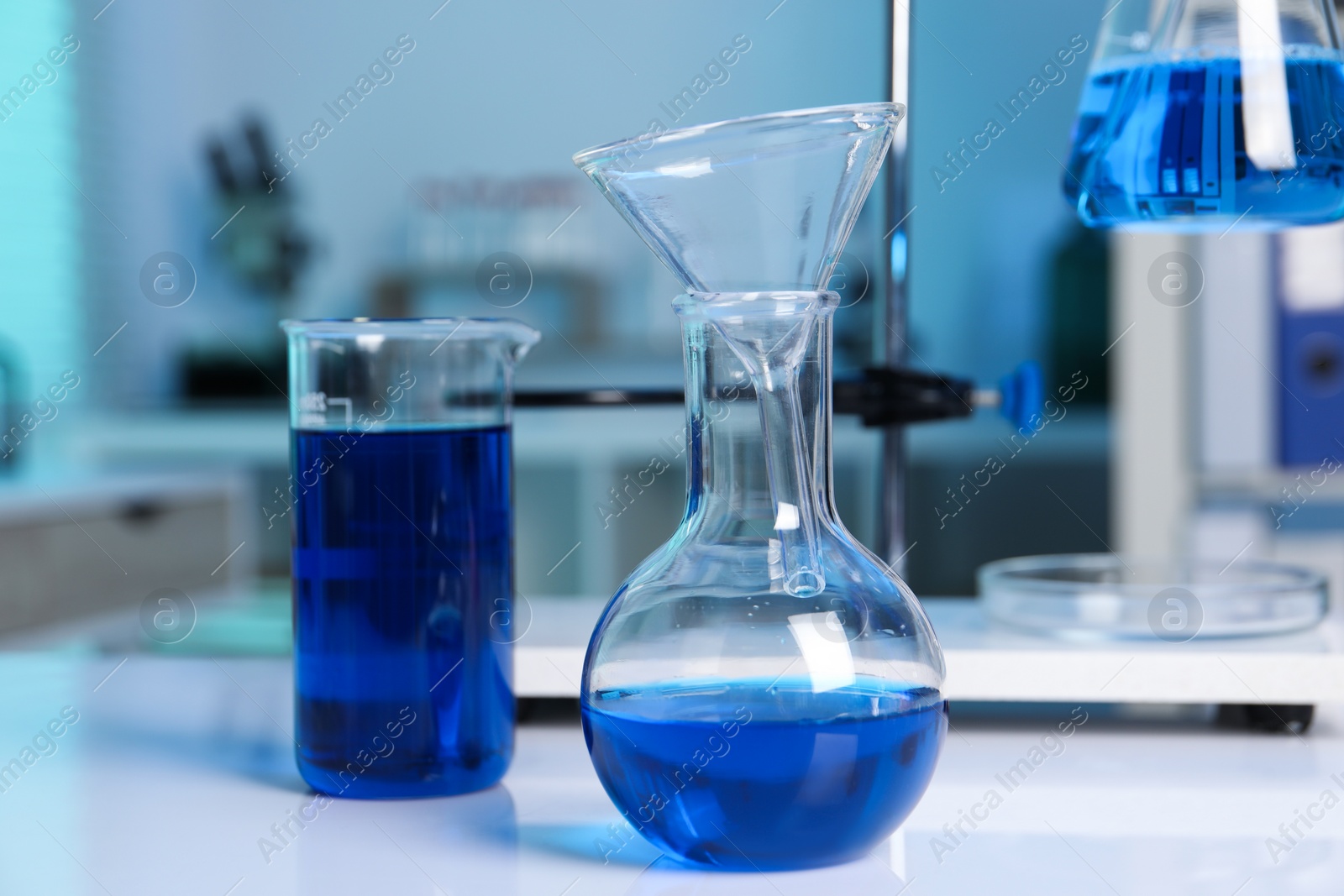 Photo of Laboratory analysis. Flasks and beaker with blue liquid on white table indoors