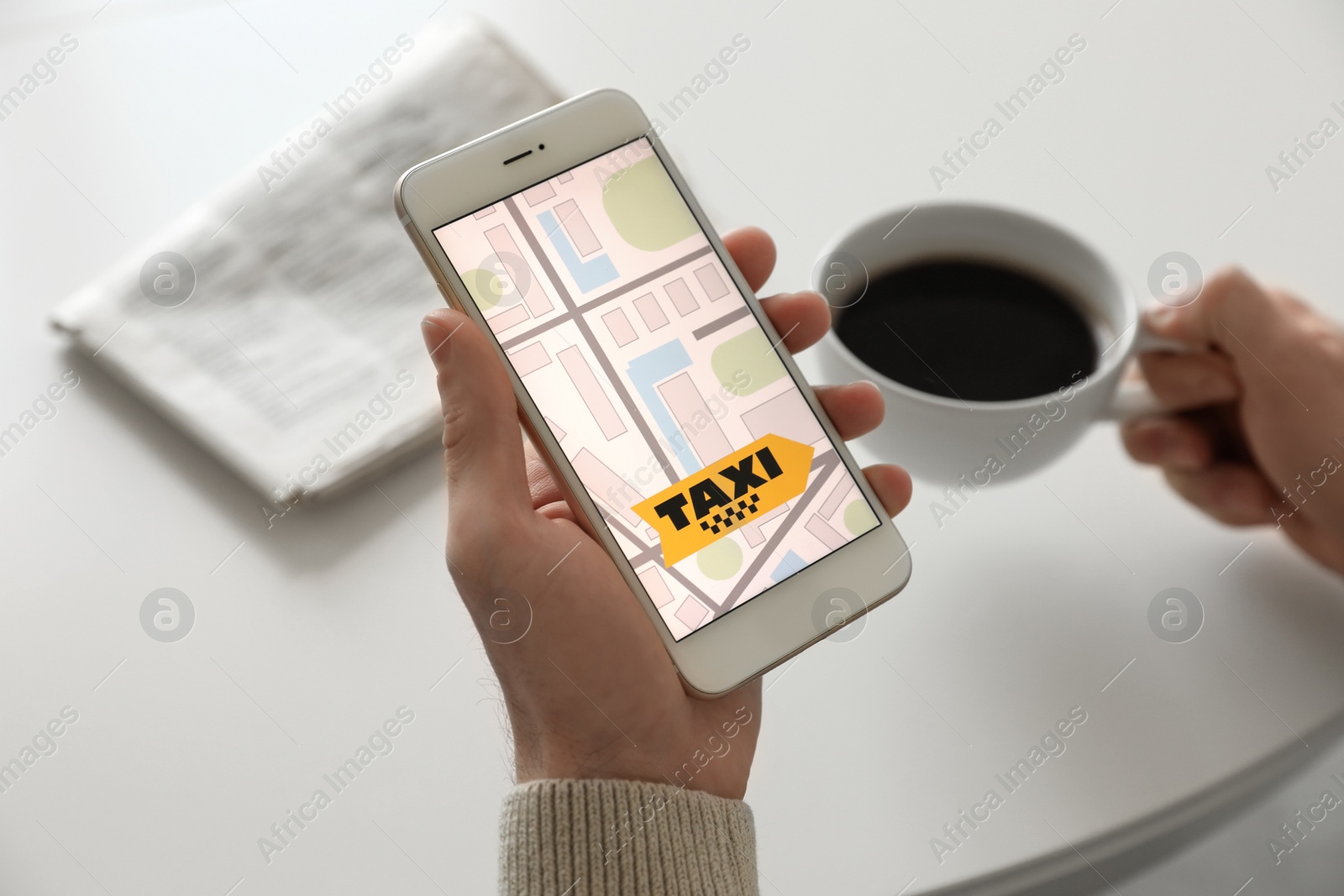 Photo of Man ordering taxi with smartphone at white table, closeup