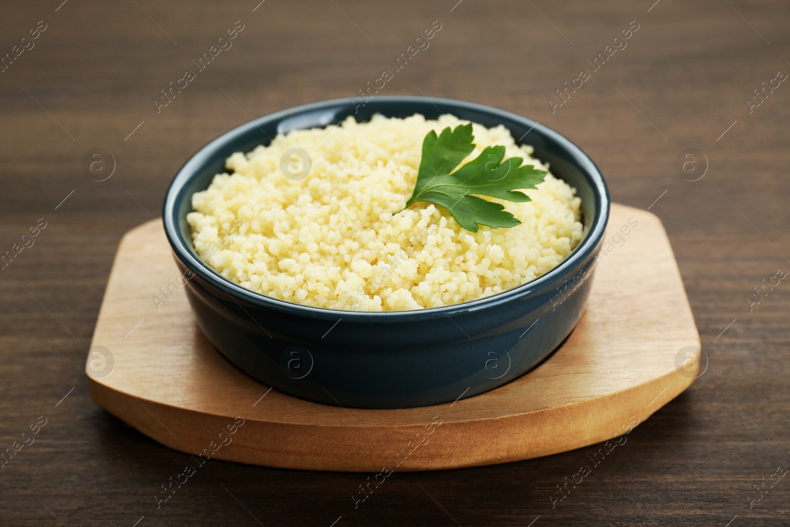 Photo of Tasty couscous with parsley on wooden table, closeup