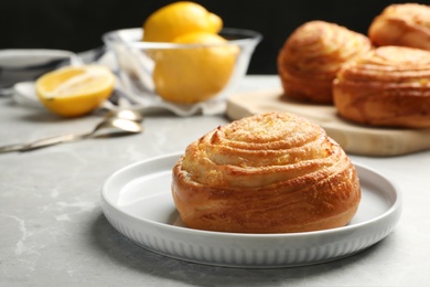 Photo of Plate with tasty bun on stone table, space for text. Fresh from oven