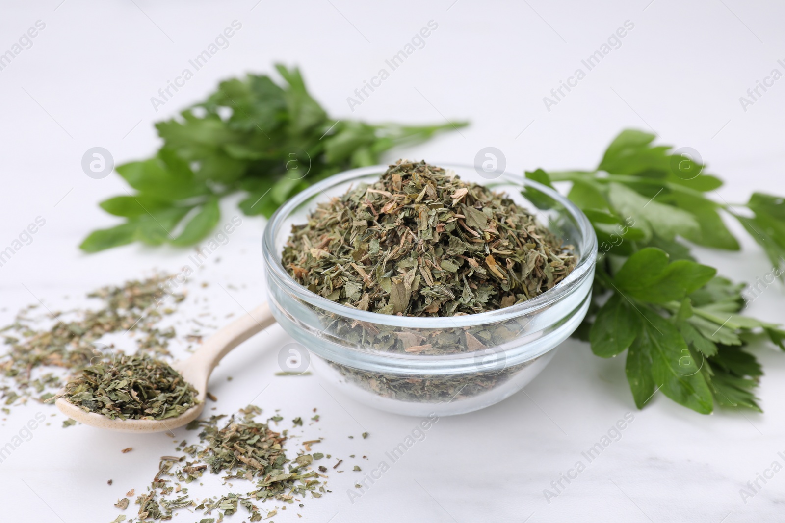 Photo of Dried aromatic parsley and fresh leaves on white table