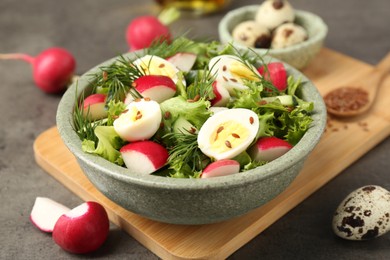 Photo of Delicious salad with radish, lettuce and boiled quail eggs on grey table, closeup