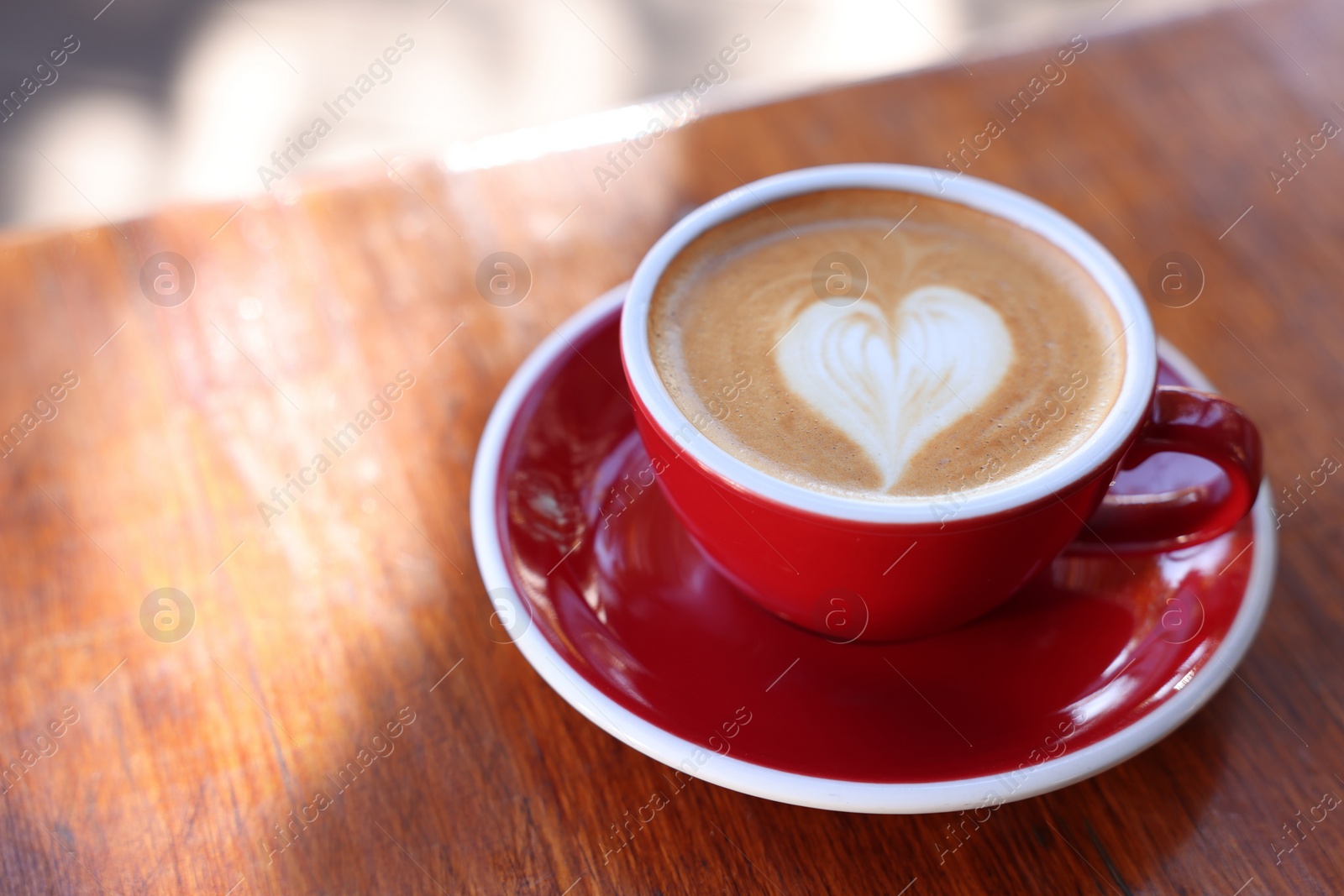 Photo of Cup of aromatic coffee with foam on wooden table. Space for text