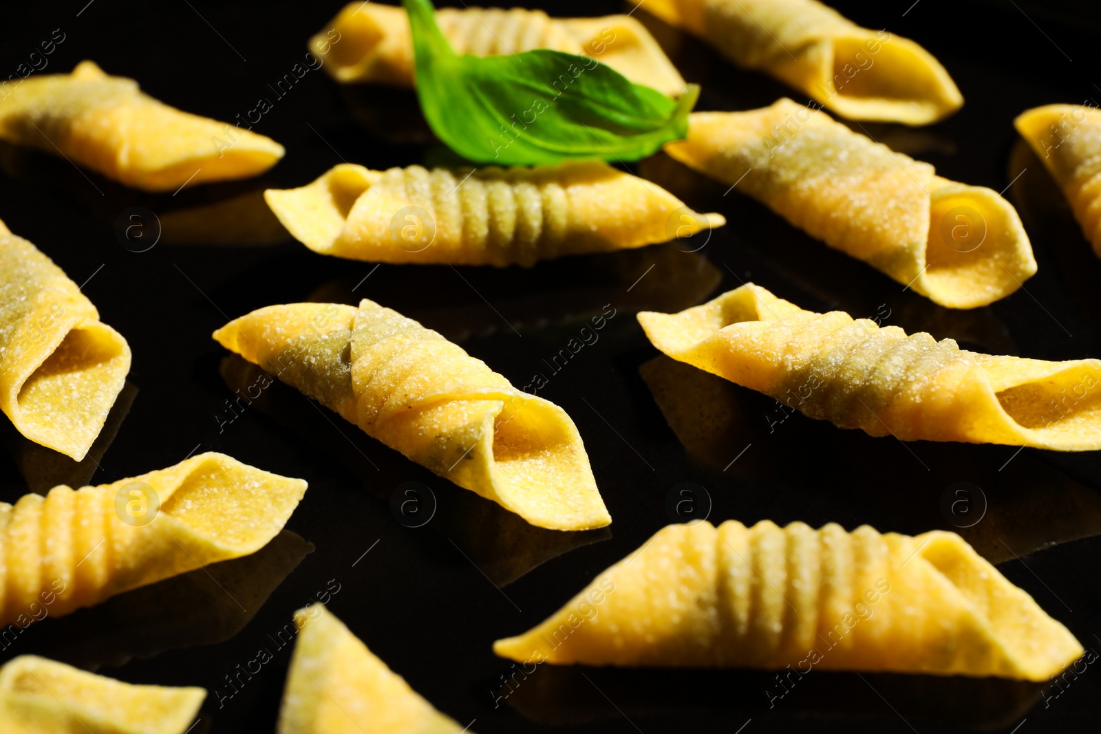 Photo of Uncooked garganelli pasta on black surface, closeup