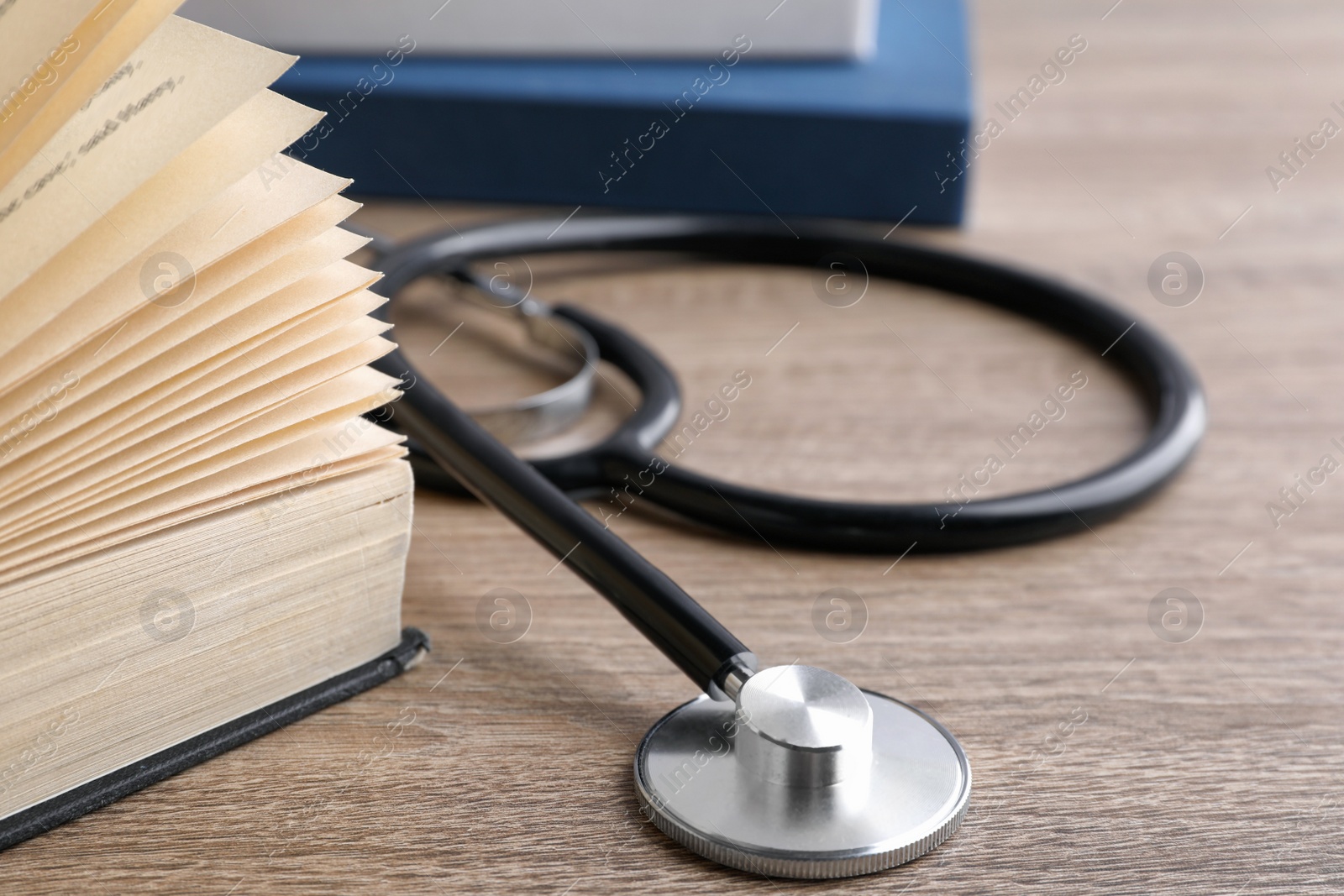 Photo of Student textbook and stethoscope on wooden table, closeup. Medical education