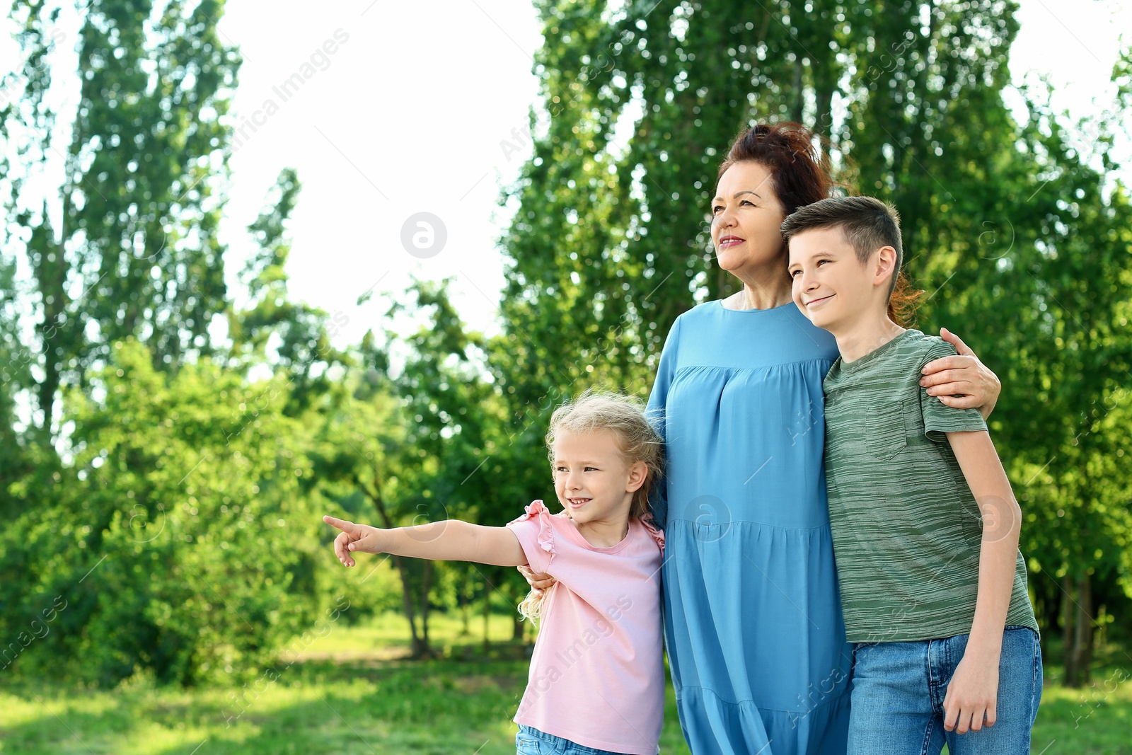 Photo of Female pensioner with grandchildren in park. Space for text