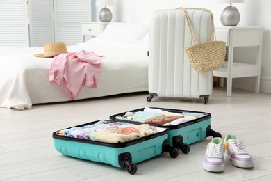 Open suitcase packed for trip and shoes on floor in room
