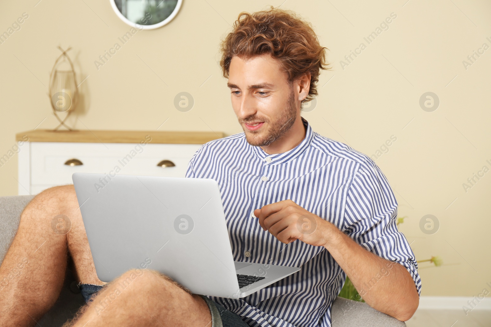 Photo of Young man with laptop sitting on sofa at home
