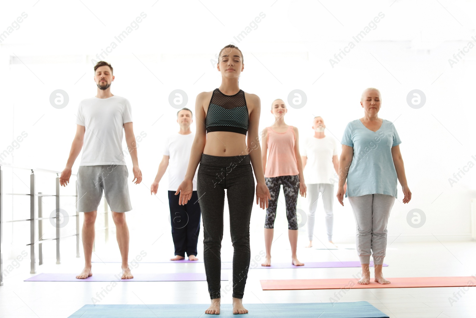 Photo of Group of people in sportswear practicing yoga indoors