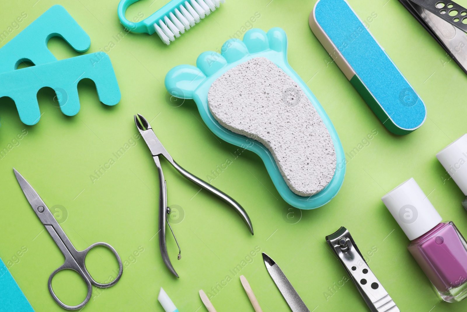 Photo of Set of pedicure tools on light green background, flat lay