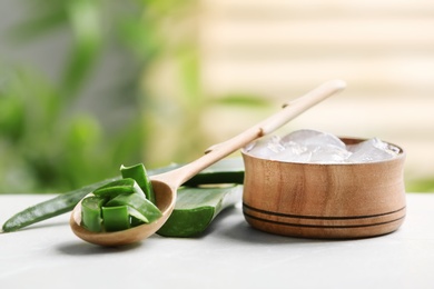 Spoon and bowl with pieces of aloe vera on table