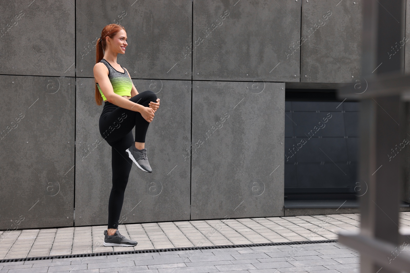 Photo of Beautiful woman in gym clothes doing exercises on street