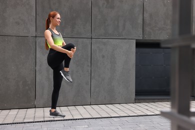 Beautiful woman in gym clothes doing exercises on street