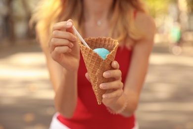 Photo of Young woman with delicious ice cream in waffle cone outdoors, closeup