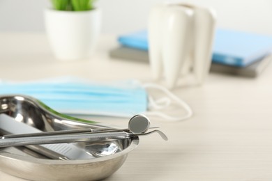 Photo of Kidney shaped tray with set of dentist's tools on wooden table, closeup. Space for text