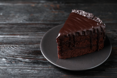 Delicious chocolate cake on black wooden table, space for text