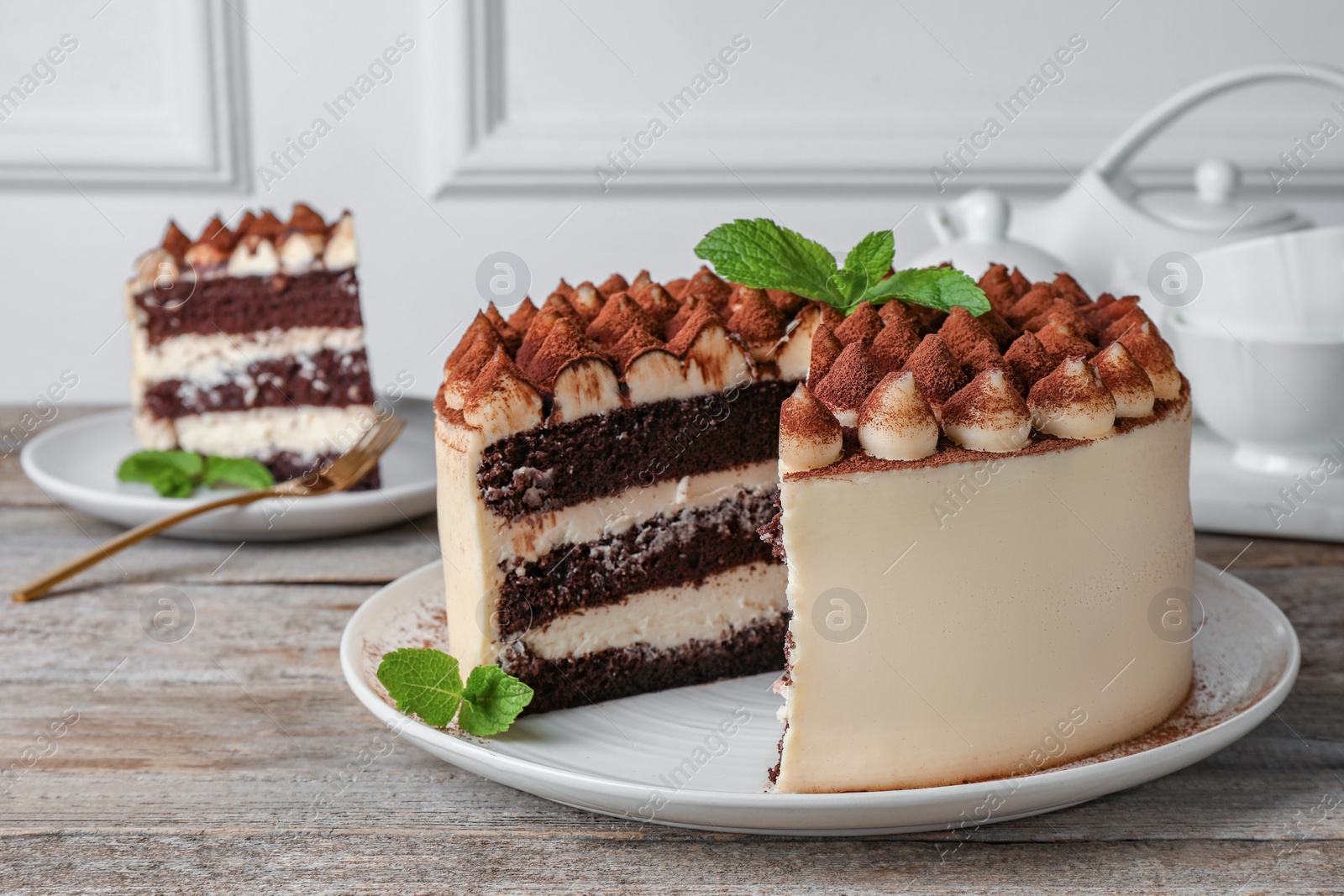 Photo of Delicious tiramisu cake with mint leaves on wooden table