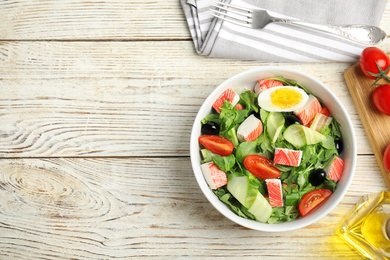 Delicious crab stick salad served on white wooden table, flat lay. Space for text