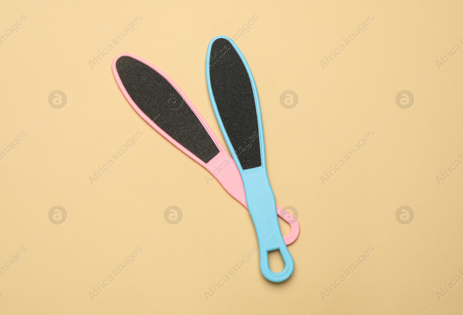 Photo of Colorful foot files on beige background, flat lay. Pedicure tools