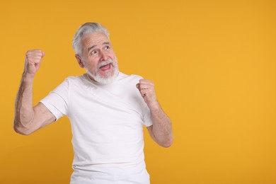 Portrait of surprised senior man on yellow background, space for text