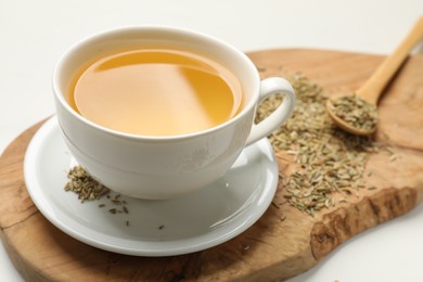 Photo of Fennel tea in cup and seeds on white table, closeup