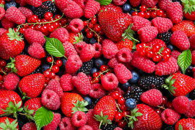 Mix of different ripe tasty berries as background, top view