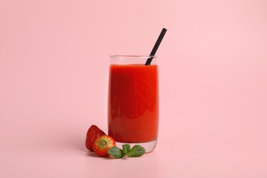 Photo of Glass with delicious berry smoothie and fresh strawberries on pink background