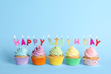 Birthday cupcakes with burning candles on light blue background