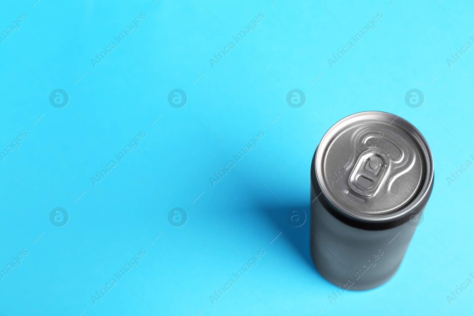 Photo of Energy drink in black can on light blue background, above view. Space for text