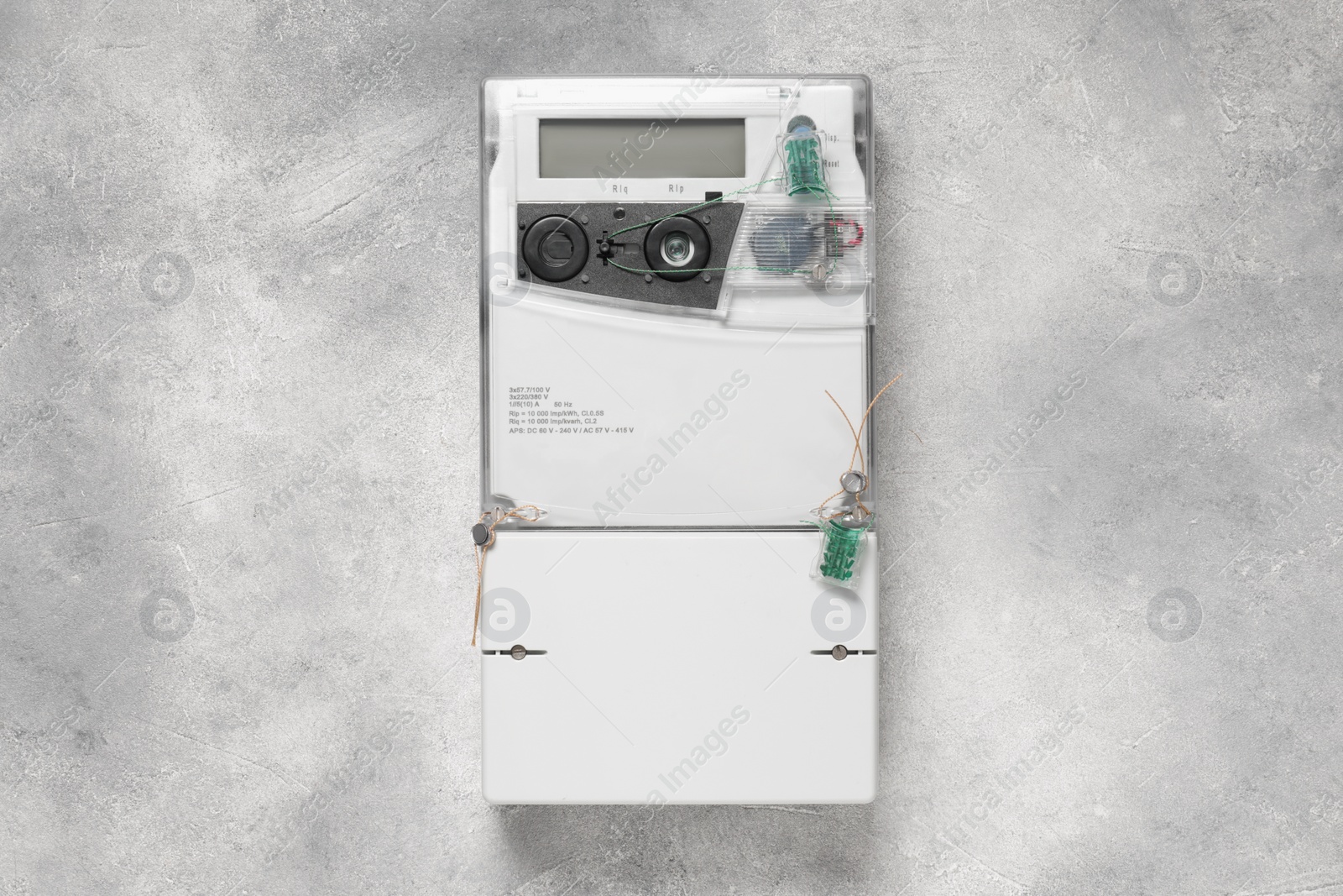 Photo of Electricity meter on light grey wall. Measuring device