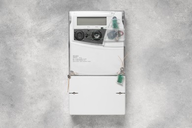 Photo of Electricity meter on light grey wall. Measuring device