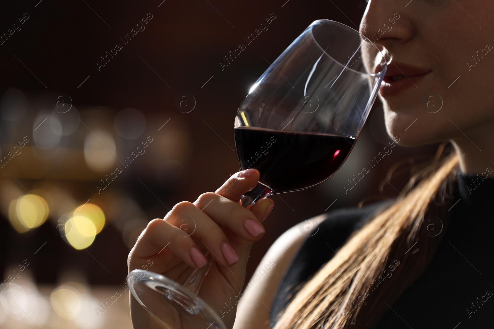 Photo of Woman with glass of red wine against blurred background, closeup. Space for text