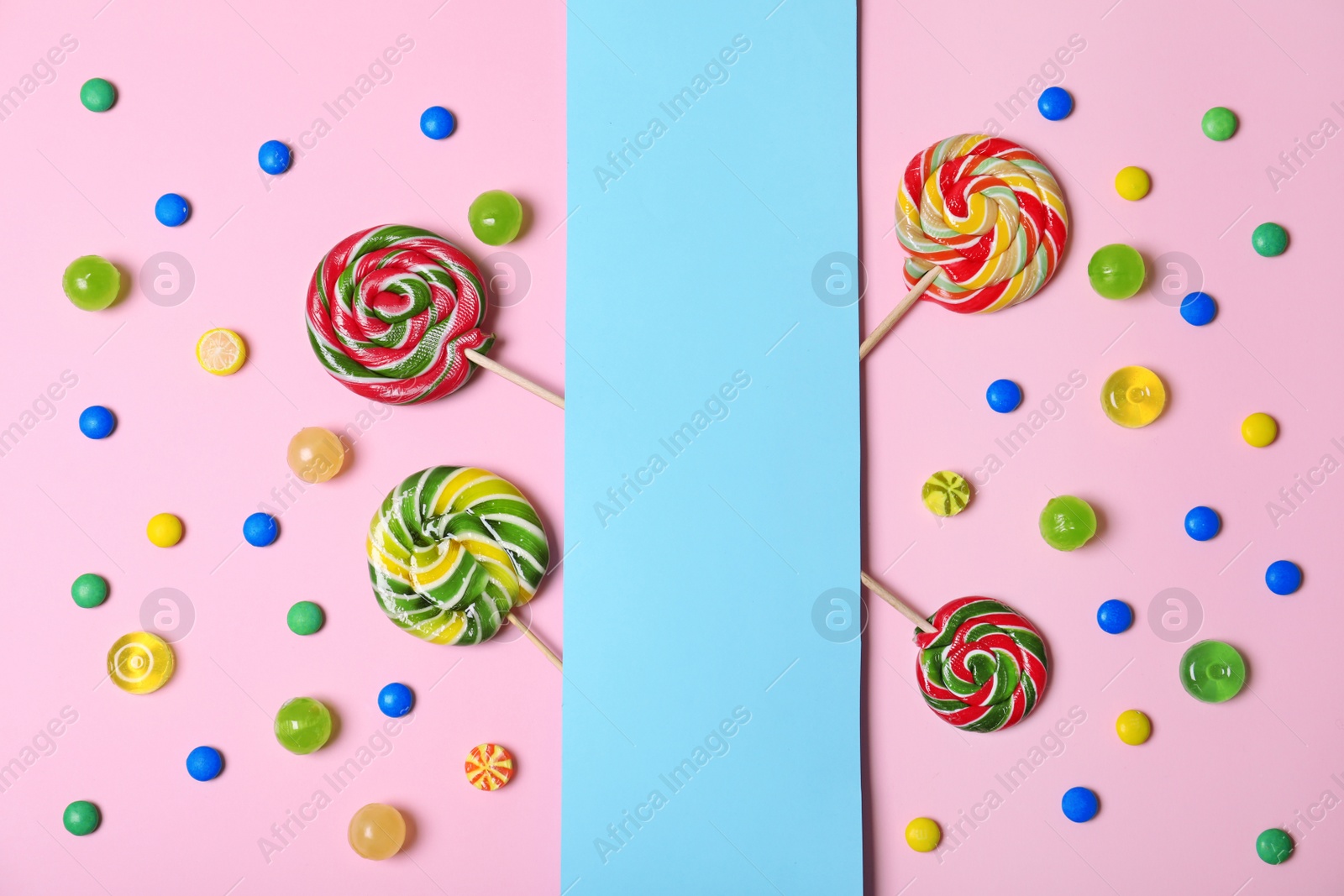 Photo of Different tasty candies and card with space for text on color background, flat lay