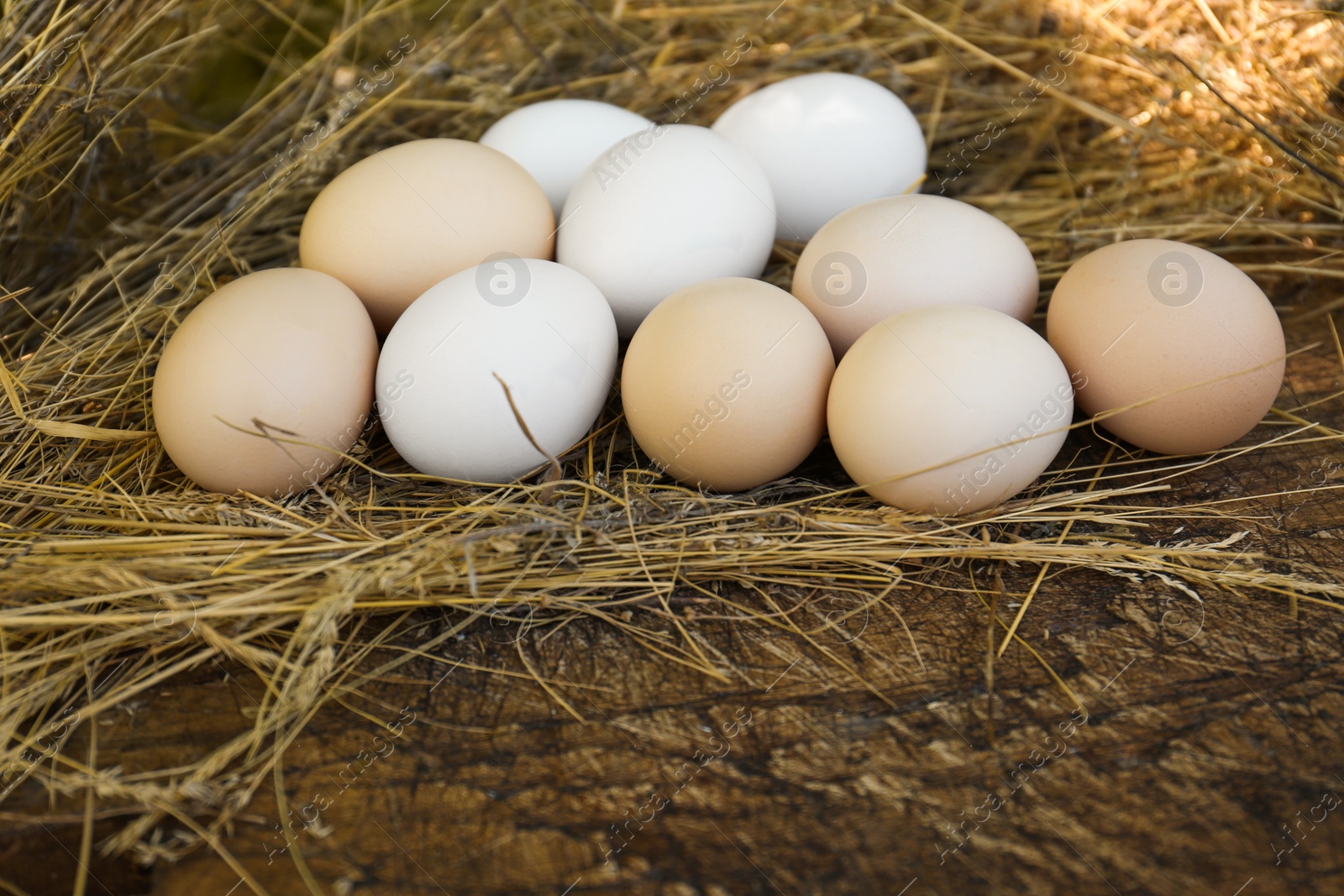 Photo of Fresh raw eggs and straw on wooden surface