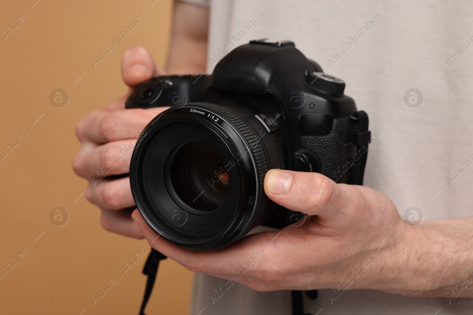 Photo of Photographer holding camera on beige background, closeup