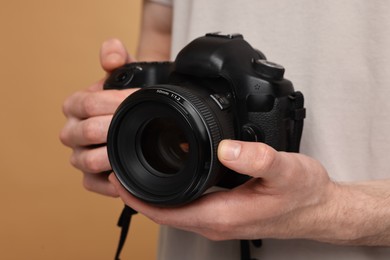 Photo of Photographer holding camera on beige background, closeup