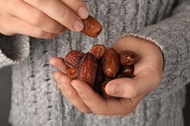 Photo of Woman holding handful of dried date fruits, closeup