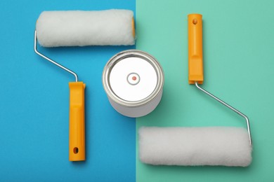 Can of orange paint and roller brushes on color background, flat lay