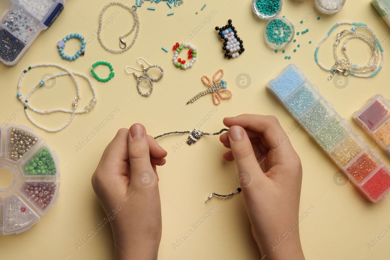 Photo of Girl making beaded jewelry on beige background, top view