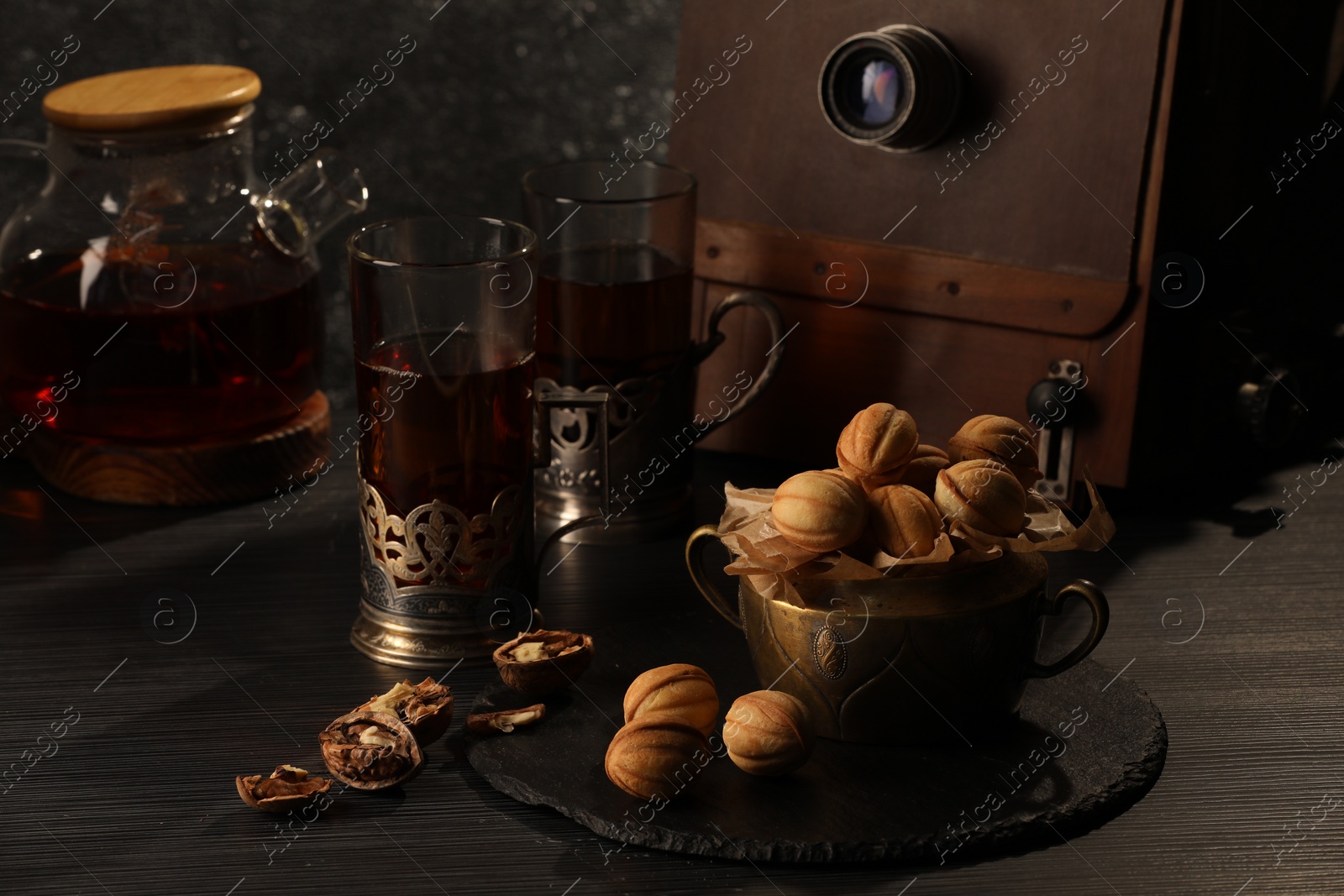 Photo of Delicious homemade walnut shaped cookies with tasty filling and walnuts on black table