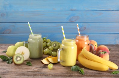 Mason jars of different tasty smoothies and fresh ingredients on wooden table