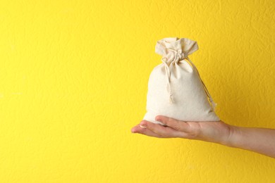 Photo of Woman holding full cotton eco bag on yellow background, closeup. Space for text