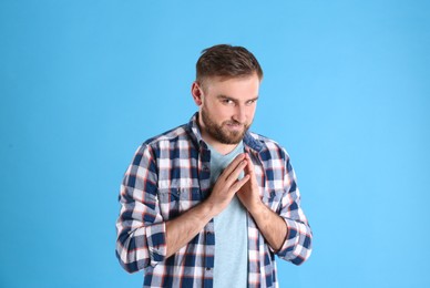 Photo of Greedy young man rubbing hands on light blue background