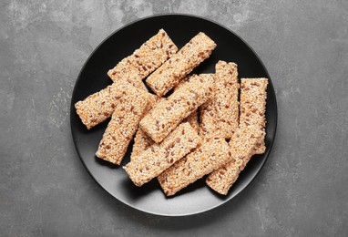 Photo of Plate with tasty sesame seed bars on grey table, top view